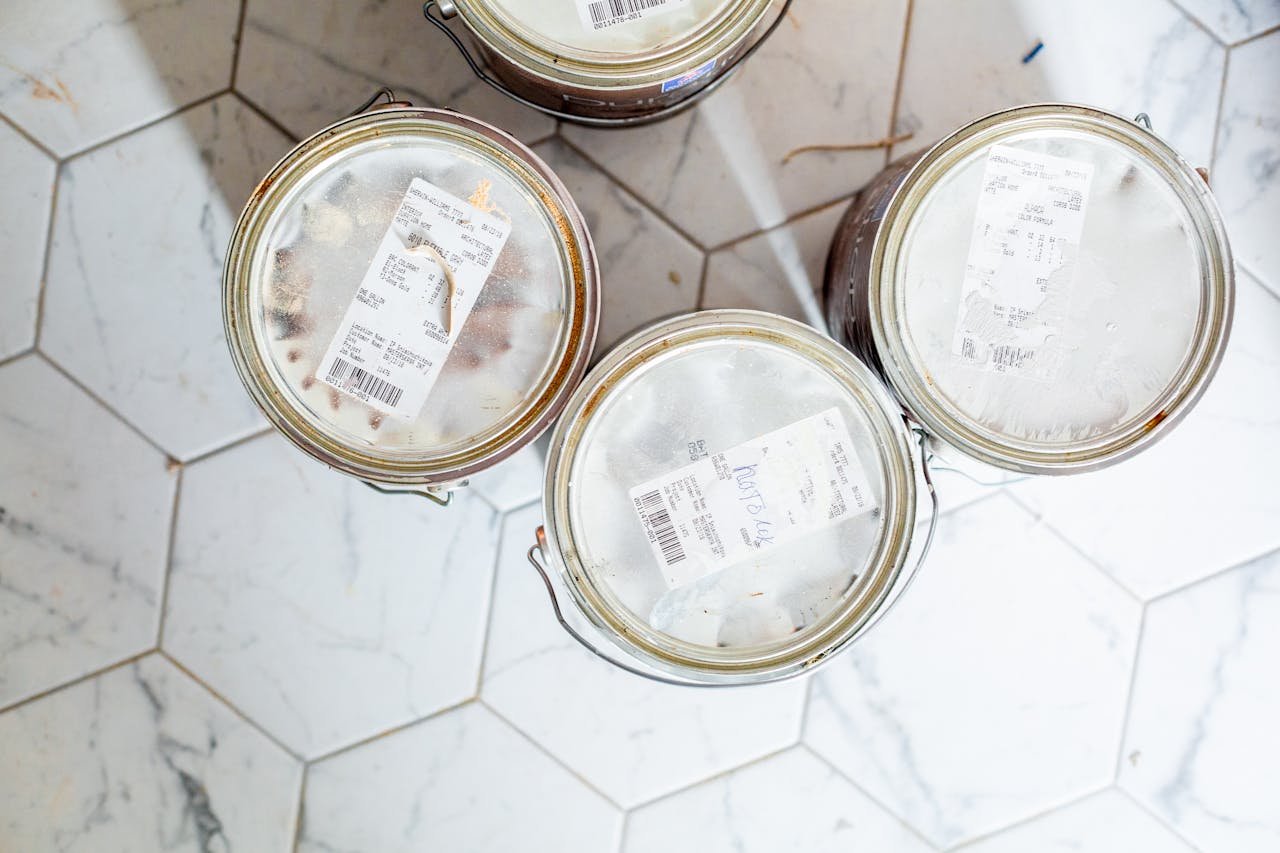 Top view of three paint cans on a hexagonal tile floor, ready for home renovation.